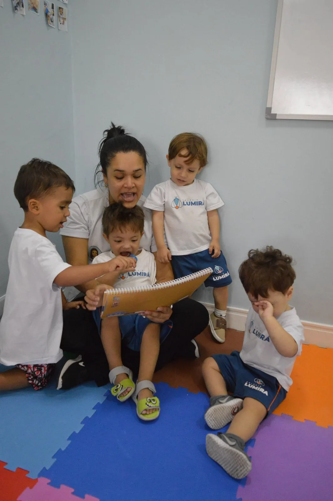Professora lendo um livro para as crianças sentadas em roda
